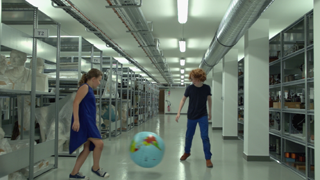 Mathias Dubreuil et Agathe van Kempen jouant avec un globe terrestre dans les réserves du matériel scientifique et didactique du Musée national de l'éducation (Munaé, Rouen). Extrait de 